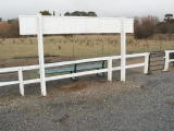 A view across the Crookwell station at the down end of the platform, with a rural landscape in the background.