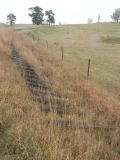 A panel of sleepers lies in a ditch just outside Roslyn on the Crookwell line. The panel may have been for the road crossing, now removed. In the background is Roslyn station.