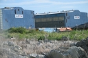 Looking south from the bottom of Moana Grove towards the railway workshop. The far right shows a new suburban development at the end of Leighton Avenue. The two locomotives appear to be a DX(?) in TranzRail blue livery, and a DA or DB (with the full-height hood in front of the cab) in the earlier red and blue livery of NZ Rail.