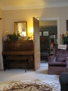 A view into the living room showing the piano, and the chair in the hall.