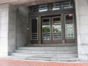 A side entrance to Wellington Railway Station. Through the doors some lights can be seen. The reflections are of buildings across the road on Bunny Street.