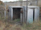 Two small sheds next to the south dock of Cooma station, looking southwest from the platform.