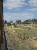 The train approaches Royalla. The signals can be seen in the distance on the left. To the right a road formation can be seen approaching the crossing.