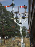 The train passes the signals north of Royalla station at crawling pace. Both signals are up, and there appear to be solar panels on the structure.
